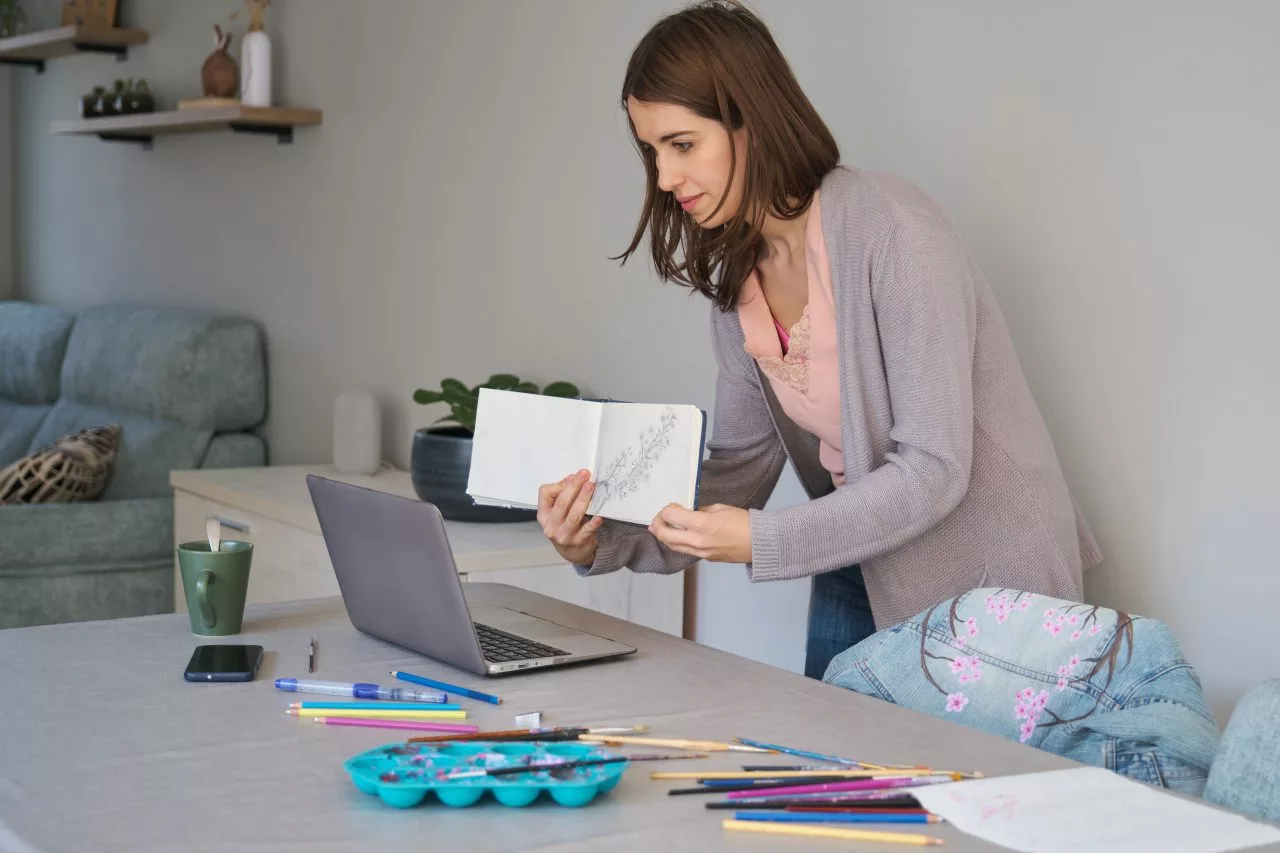 caucasian-influencer-woman-showing-her-sketchbook-to-her-community-in-a-stream-e1697192153498